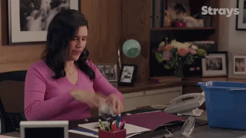 Frau, die genervt ihre Arbeit fallen lässt und frustriert ausatmet.