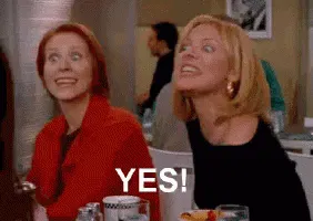 two women are sitting at a table in a restaurant and one of them is smiling and saying yes .