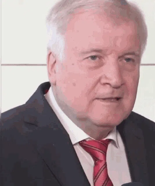 a close up of a man in a suit and tie talking into a microphone .