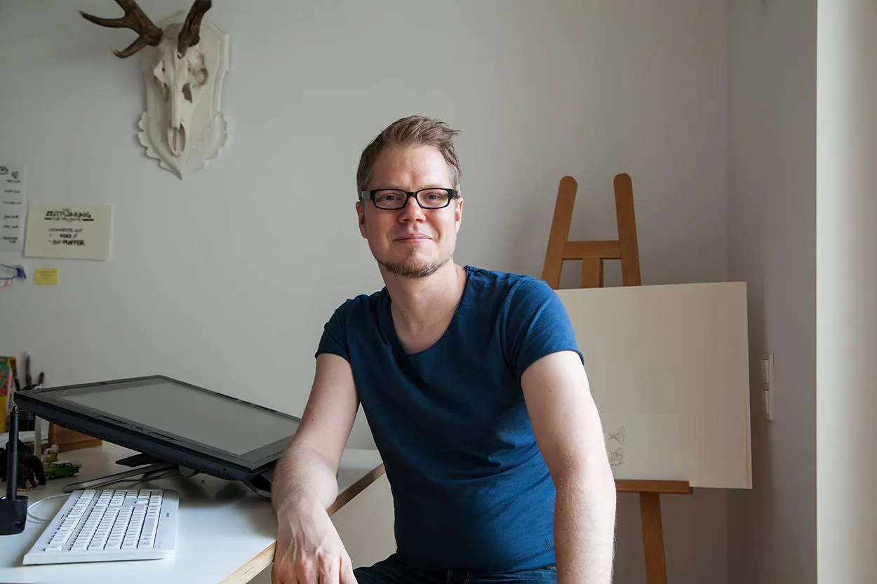 Der Comiczeichner Flix sitzt an seinem Arbeitstisch.