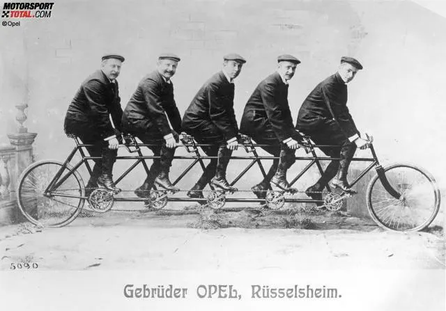 Eine alte Fotografie, fünf Männer auf einem einzigen Fahrrad. Die Gebrüder Opel.