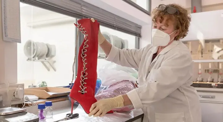Laborantin schaut sich hochhackigen, roten Stiefel an